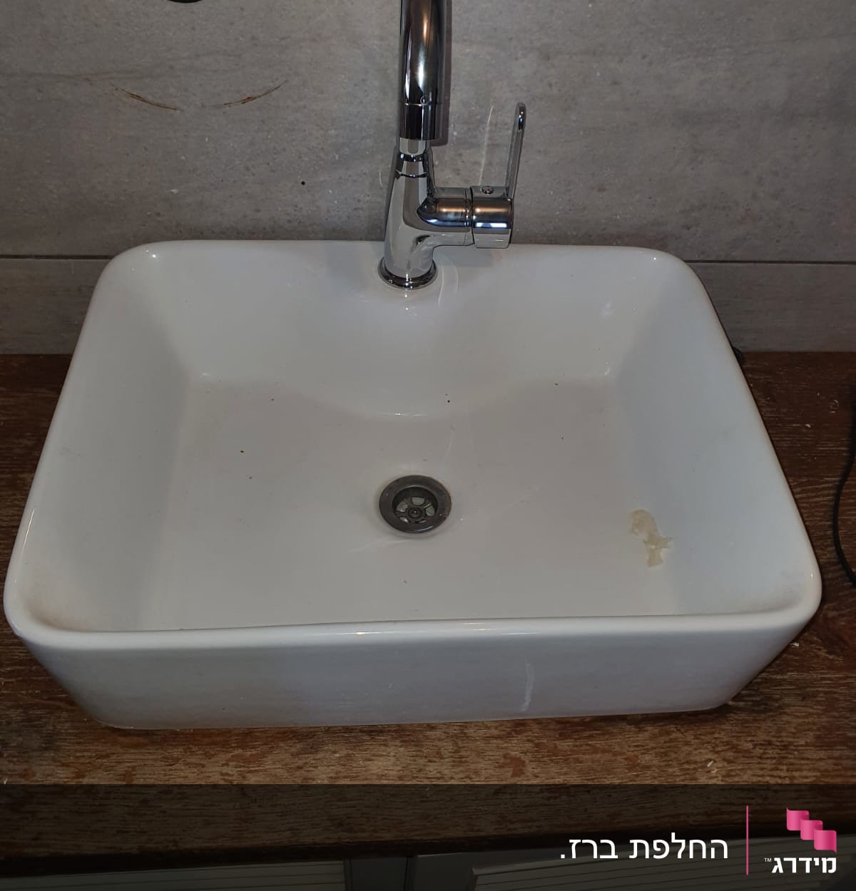 כיור לבן עם ברז כרום על משטח עץ